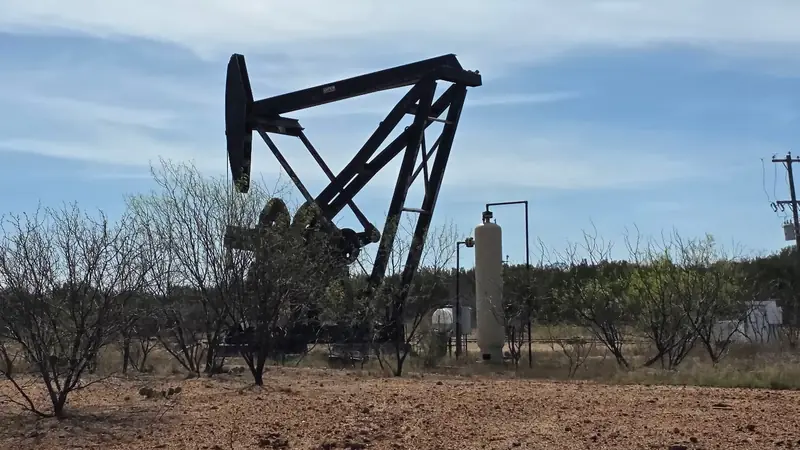 A second beam pumping unit on the lease with low scrub in the foreground