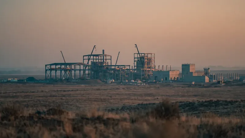 A large industrial plant under construction on open ground at dusk