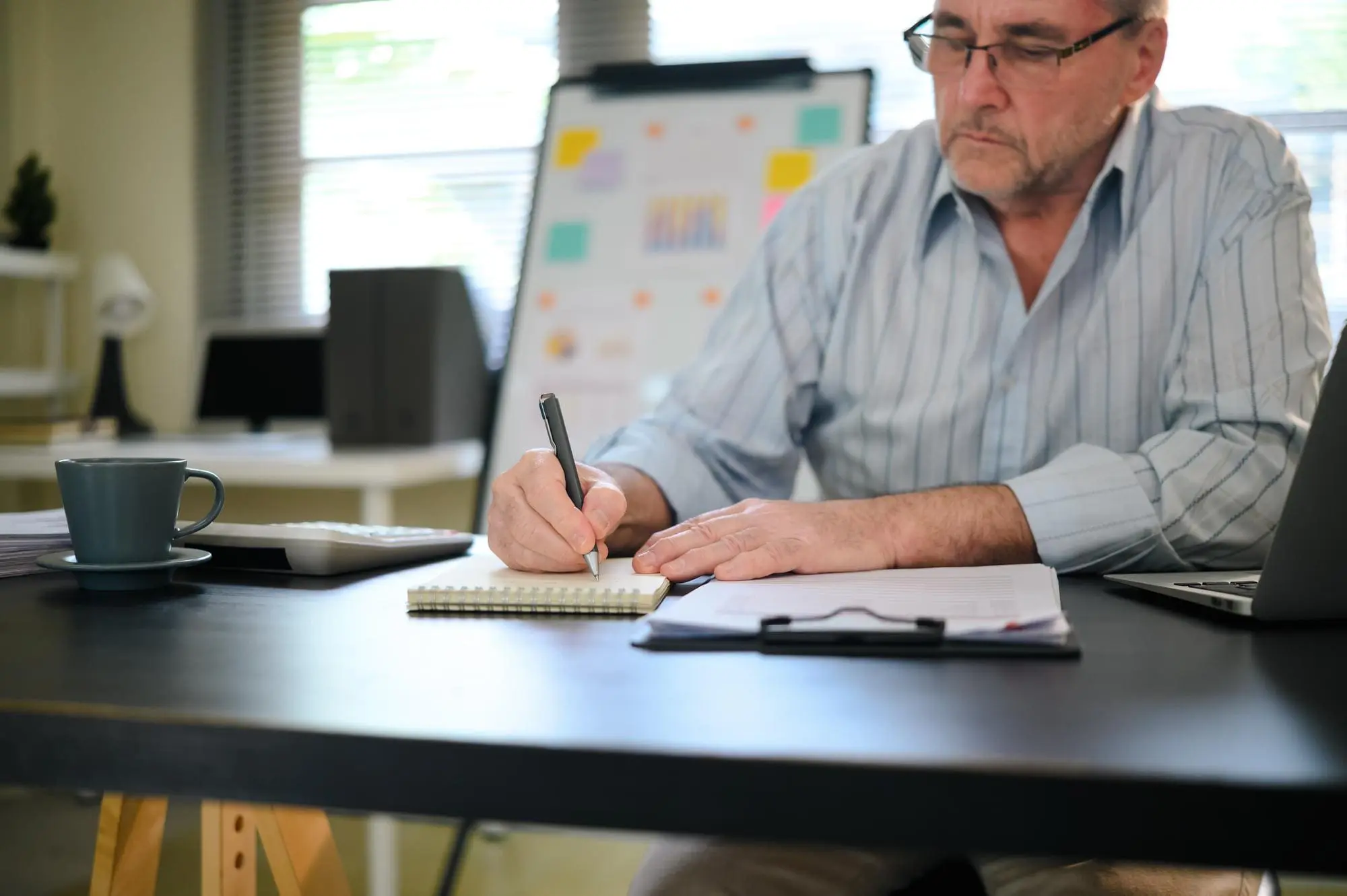 Senior businessman working at desk writing and analyzing documents