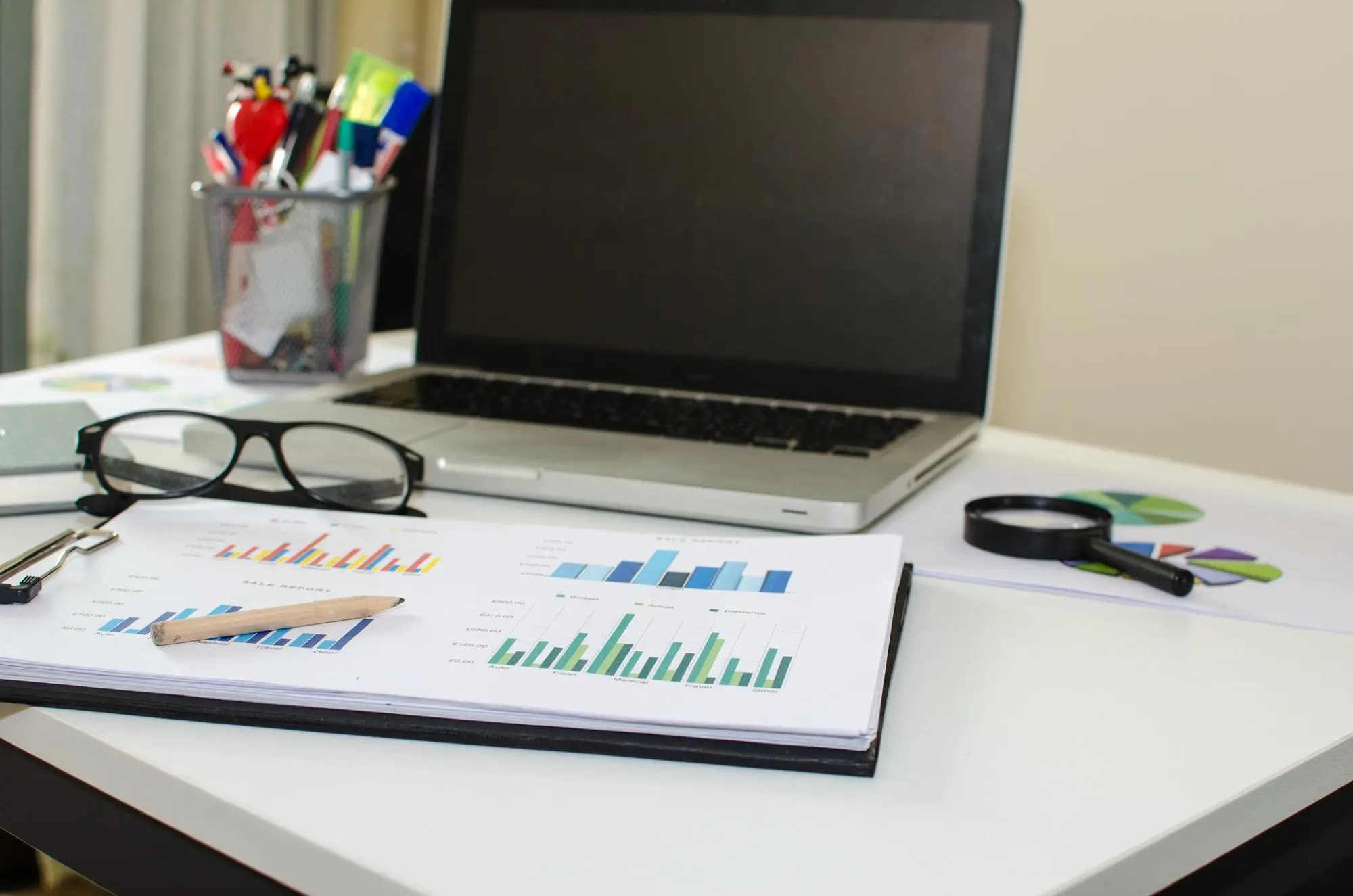 Close-up of laptop and documents on desk in office