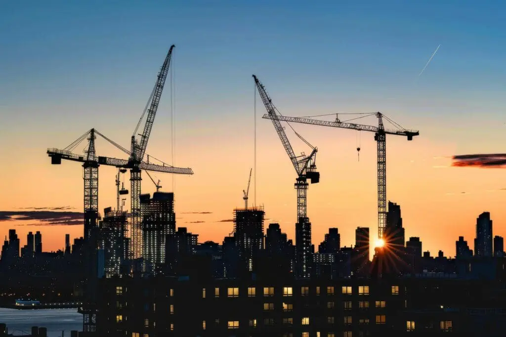 Construction cranes on a city skyline at dusk